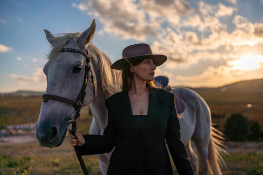 Woman horse sunset elegant fashion portrait with white mare at golden hour