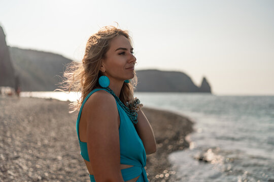Woman, beach, summer. Relaxed blonde woman enjoying peaceful sunset moment on tranquil pebble beach by the sea.
