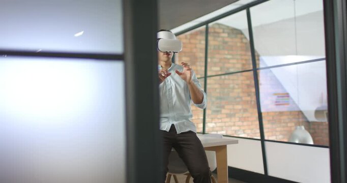 VR app launching, Asian man in blue shirt wearing VR headset gesturing, examining model at desk