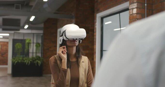 African American woman raising hand, pinching and tapping, testing VR headset controls in office