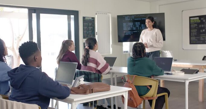 Indian teacher with teens in lab asking question while teens with laptops raising hands to answer