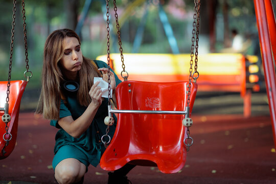 Worried Mother Cleaning Public Park Swing With Antiseptic Wet Wipes. Anxious mom wiping playground equipment carefully to protect her child from dirt and outdoor germs
