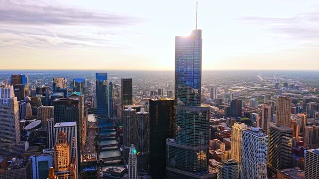 Sunset aerial view of towers and Chicago River. Drone perspective captures glass skyscrapers, bridges and warm evening light downtown.