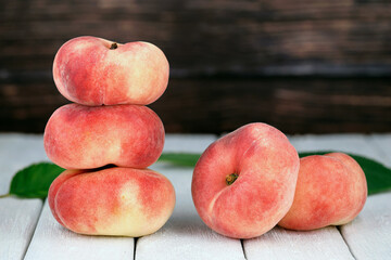 Fresh Flat Peaches, Saturn Peaches, Prunus persica var. platycarpa, on White Wooden Table with Rustic Background © Andreas