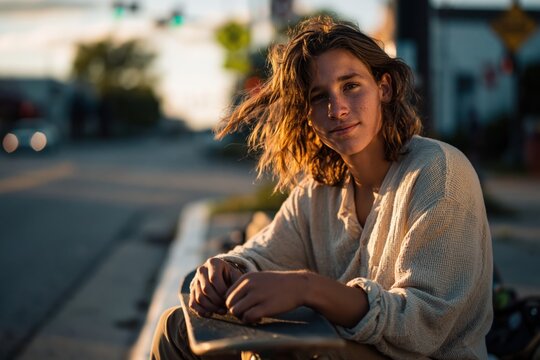 Teenage boy adjusts his skateboard on the street during sunset in an urban environment