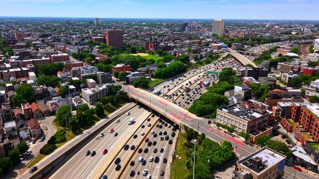 Aerial view of expressway interchange, Chicago. Overhead drone perspective shows multilane traffic, an overpass bridge and dense residential rooftops under clear blue sky.