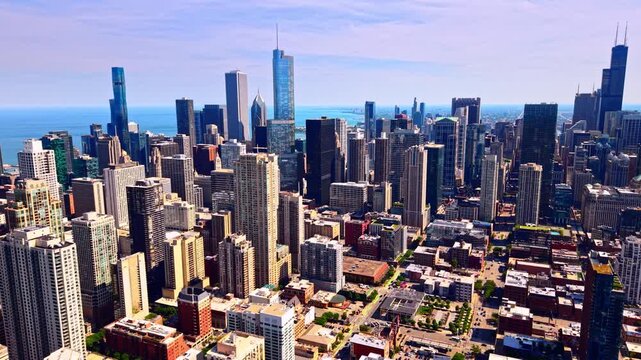 Elevated view of Chicago skyscrapers along the lakefront. Rows of downtown towers rise against a hazy sky, with Lake Michigan stretching along the horizon in soft afternoon light.