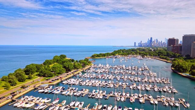 Rows of docked boats along Lake Michigan marina, Chicago, Illinois. Wide aerial view shows a full harbor beside green shoreline park, with the downtown skyline visible on the horizon.