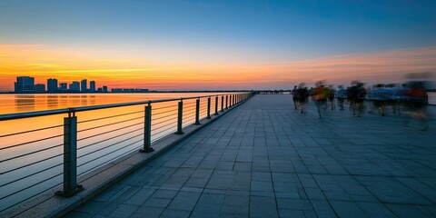 Obraz premium A pier at sunset with distant cityscape and blurred figures exercising