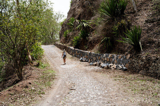 Woman with backpack hikes up a cobblestone road