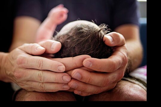 Fathers hands gently cradling his newborn baby