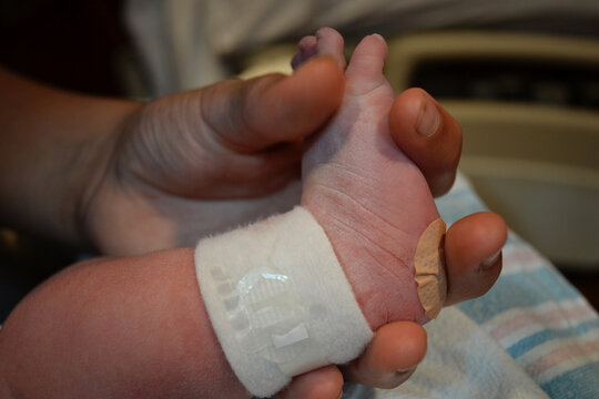 Parent gently holding a newborn baby's tiny foot