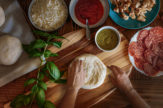Overhead view of hands making homemade pizza from scratch