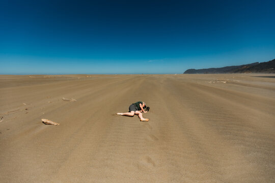 Person lying face down on a vast empty beach