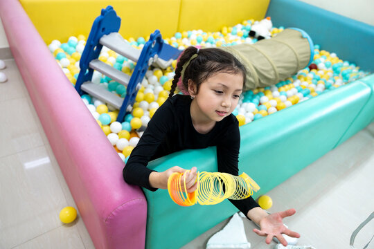 Girl playing with spring toy in ball pit