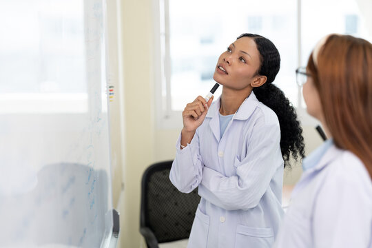African American scientist writing on whiteboard in laboratory