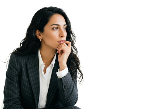 Woman sits in business suit with chin resting on her hand. She looks off to the side in a bright setting with clear white space. Concept of business, career mindset, professional thinking
