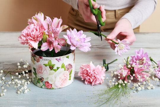 Florist at work: woman shows how to make flower box with alstroemerias, chrysanthemums and carnations in cute pink color, suitable for wedding or birthday present. Step by step, tutorial.