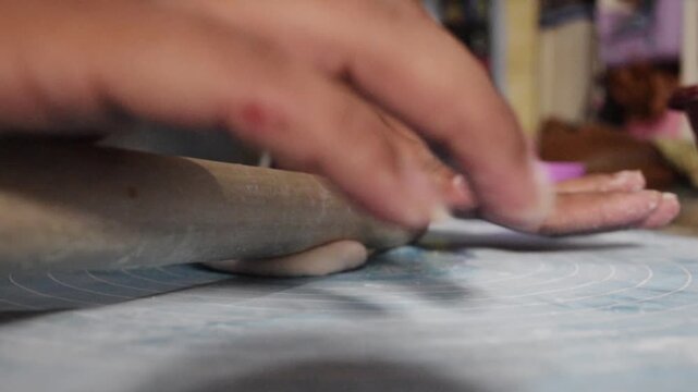 Close up of cireng dough passing through a roller manual with rolling pin during Indonesian traditional snack production. Perfect for food manufacturing and culinary industry concepts.