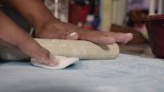 Asian worker is flatting cireng dough during Indonesian traditional snack production. Ideal for food industry, manufacturing, and commercial kitchen concepts.