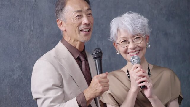 カラオケでマイクを持って歌うシニア男女