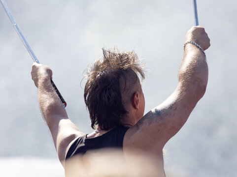 Man holds poles above head, back turned