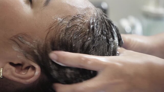 Southeast Asian woman receiving shampoo and scalp massage therapy at a Japanese head spa with water halo setup for relaxation and scalp wellness.