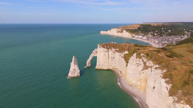 Pulling back from the cliff face, a drone reveals the sea arch and needle rock at Etretat.