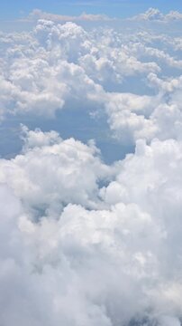 Stunning aerial footage flying through soft white cumulus clouds against a vibrant blue sky.