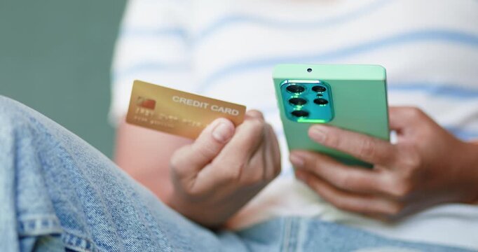 Woman holding a smartphone and credit card for online shopping and digital payment via e-commerce app. Concept of fintech, cashless transaction, secure online purchase and mobile banking, close-up
