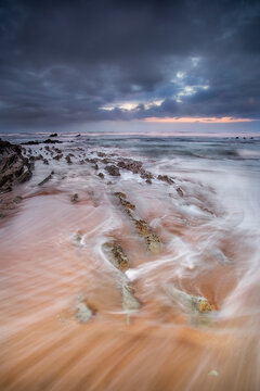  Dramatic sun rays over flysch rock formations at Sopelana beach in Bizkaia Basque Country during long exposure seascape photography