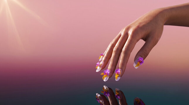Elegant hand with surreal frosted glass and spring flower manicure over a reflective surface on a pastel pink gradient background with ample copy space