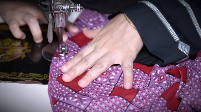 Close-up of woman hands using manual sewing machine on patterned fabric