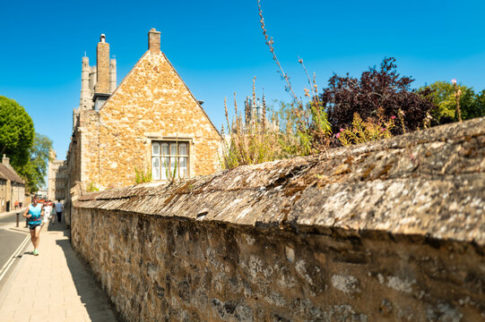 Shallow focus of a medieval wall in the famous cathedral town of Ely in Cambridgeshire, UK. A narrow pavement and a runner can be seen in the distance.