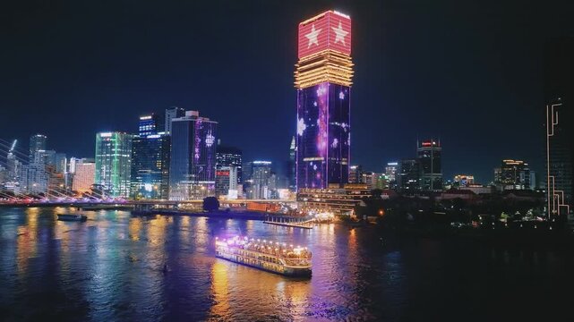 Aerial View of Dinner Cruise Boat Navigating Saigon River at Night in Ho Chi Minh City, Vietnam
bright boat searchlights, colorful reflections across the water, the lit-up cable-stayed bridge