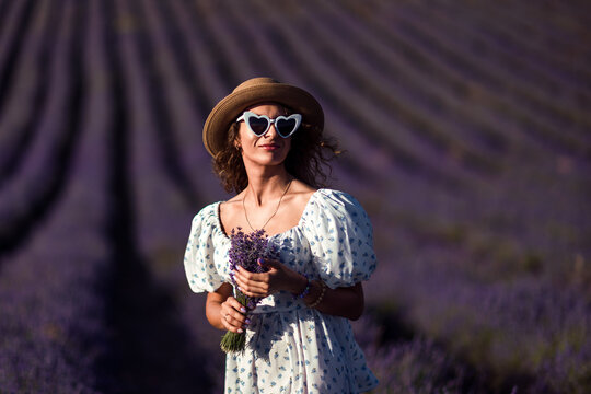Woman lavender field straw hat posing with bouquet at sunset