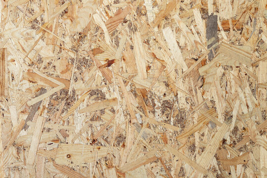 Close up of compressed wooden chipboard sheet surface. Abstract texture of pressed timber flakes and wood shavings used in construction and carpentry.