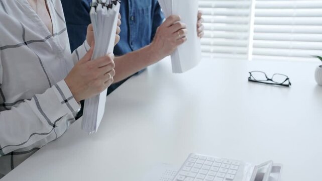 Business professionals analyzing financial data and working together, reviewing charts, graphs, and documents on a white desk during an important office meeting to strategize future growth
