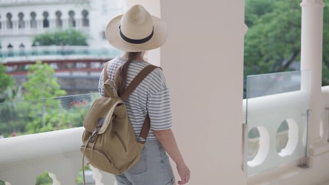 Female tourist in hat with backpack is walking along galleria