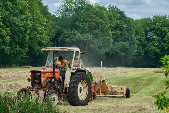 Agricultural hay production in Hoogeveeen Netherlands farmer operating old tractor making hay bales in a rural field Traditional farming practices and sustainable agriculture