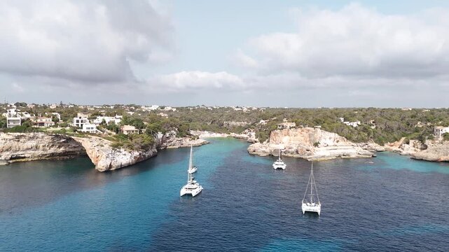 A drone shot of Cala Lombardes beach in Mallorca, that pans around a couple of boats anchored in the water. The footage was taken on 24th July 2026.
