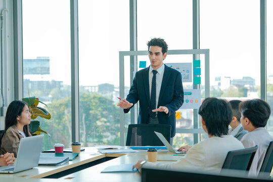 Business executive presents key performance metrics during meeting. Team reviews charts, shares ideas, discusses planning, develops strategy, improves communication, supports growth.