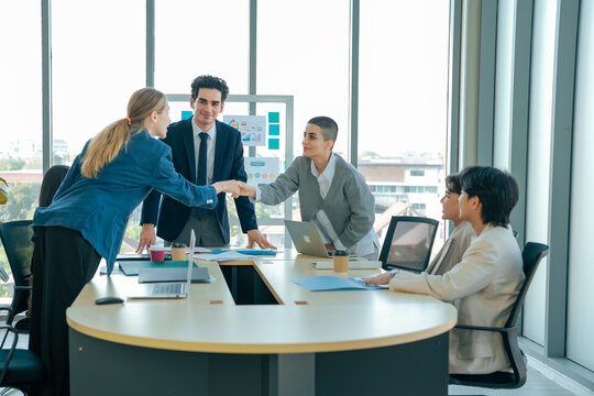 Business colleagues shake hands after successful meeting while manager observes. Team celebrates agreement, partnership, collaboration, trust, professional relationship, shared business success.