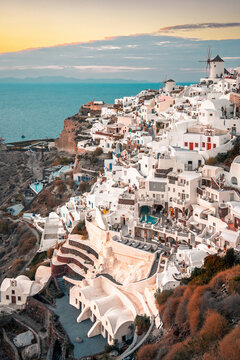 White buildings and windmills spread along the cliffside of oia village in santorini