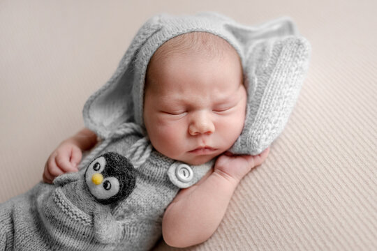 Newborn baby sleeps peacefully on soft cream blanket. Professional newborn photoshoot.