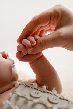 Small infant hand grasps adult finger. Tender moment of new connection.