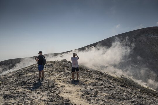 Tourists stand at the crater rim and photograph rising sulfur clouds, Vulcano, Aeolian or Lipari islands, Sicily, southern Italy, Italy