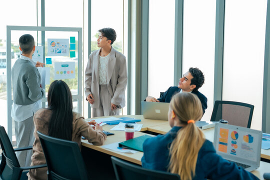 Team leaderl speaker presents infographic report during conference while executive team reviews business strategy, communication, planning, leadership, organizational growth, shared achievement.