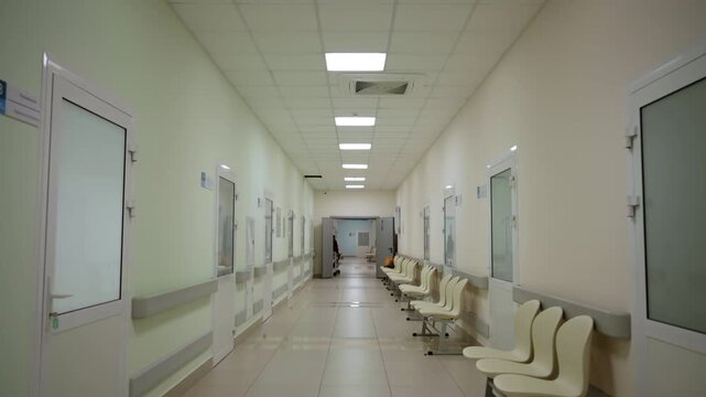 Corridor features square ceiling lights shining over closed clinical doors. Symmetrical alignment creates structured hospital atmosphere