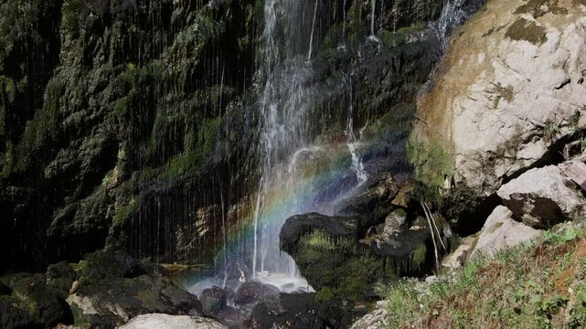 Static shot of Wasserlochklamm waterfall with a bright rainbow in the water mist, Palfau, Austrian Alps